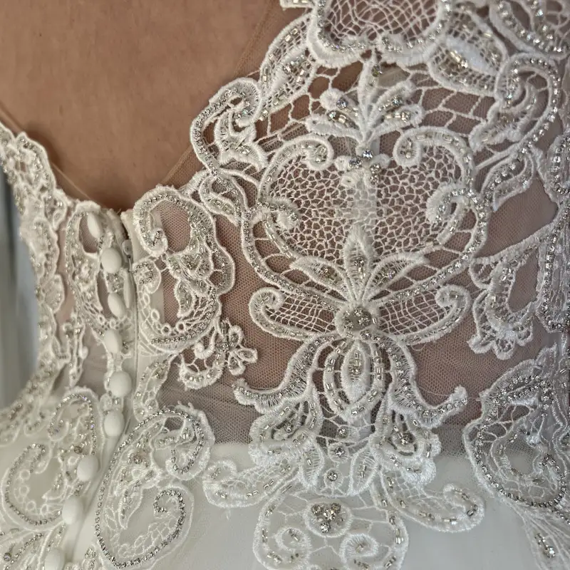 Spitze mit Perlen und Knopfleiste am Rücken eines Brautkleides